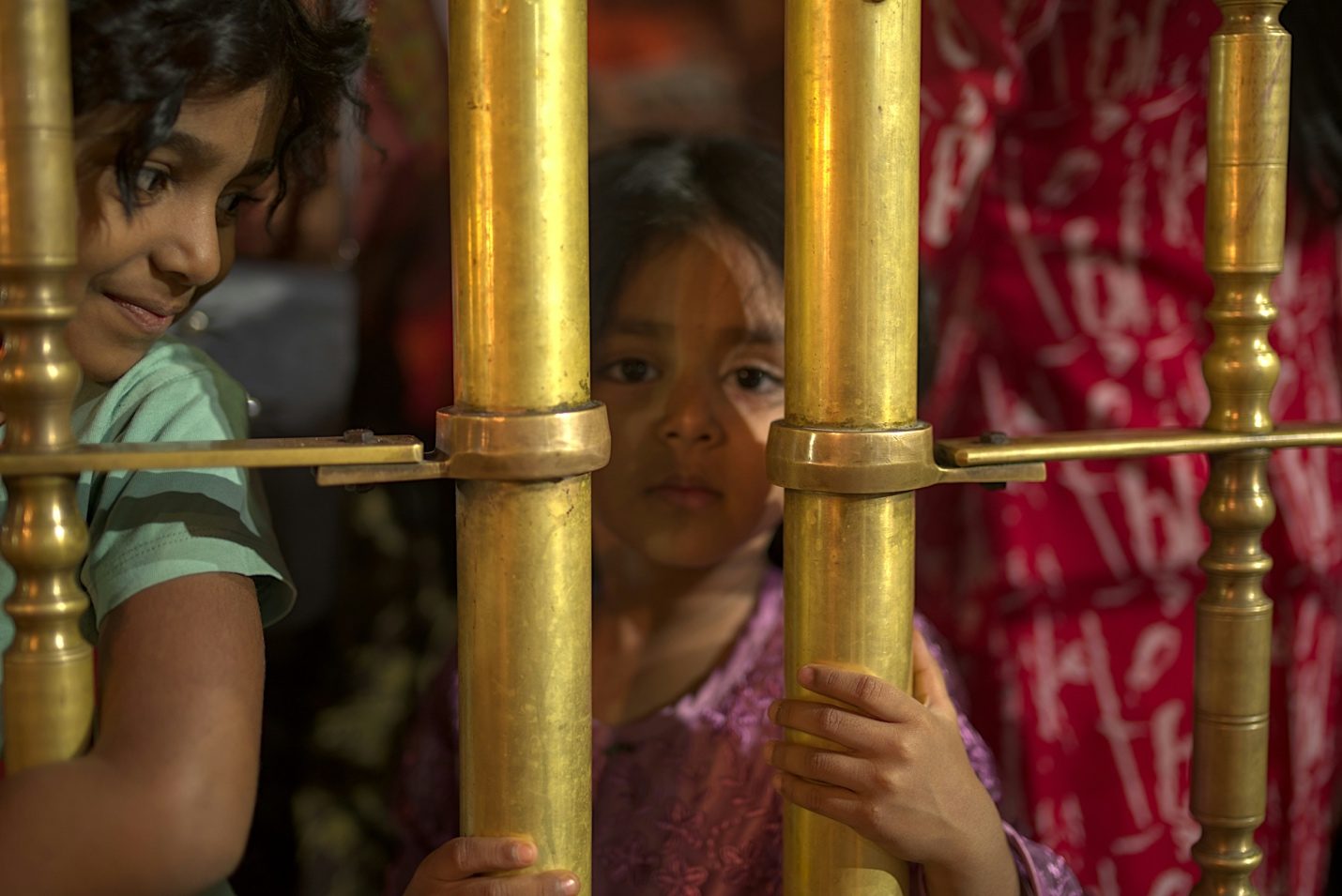 Children looking out through metal bars